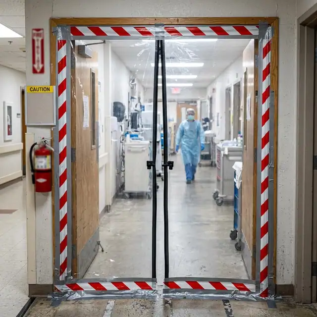 Sealed corridor entry with a plastic zipper style barrier and warning tape